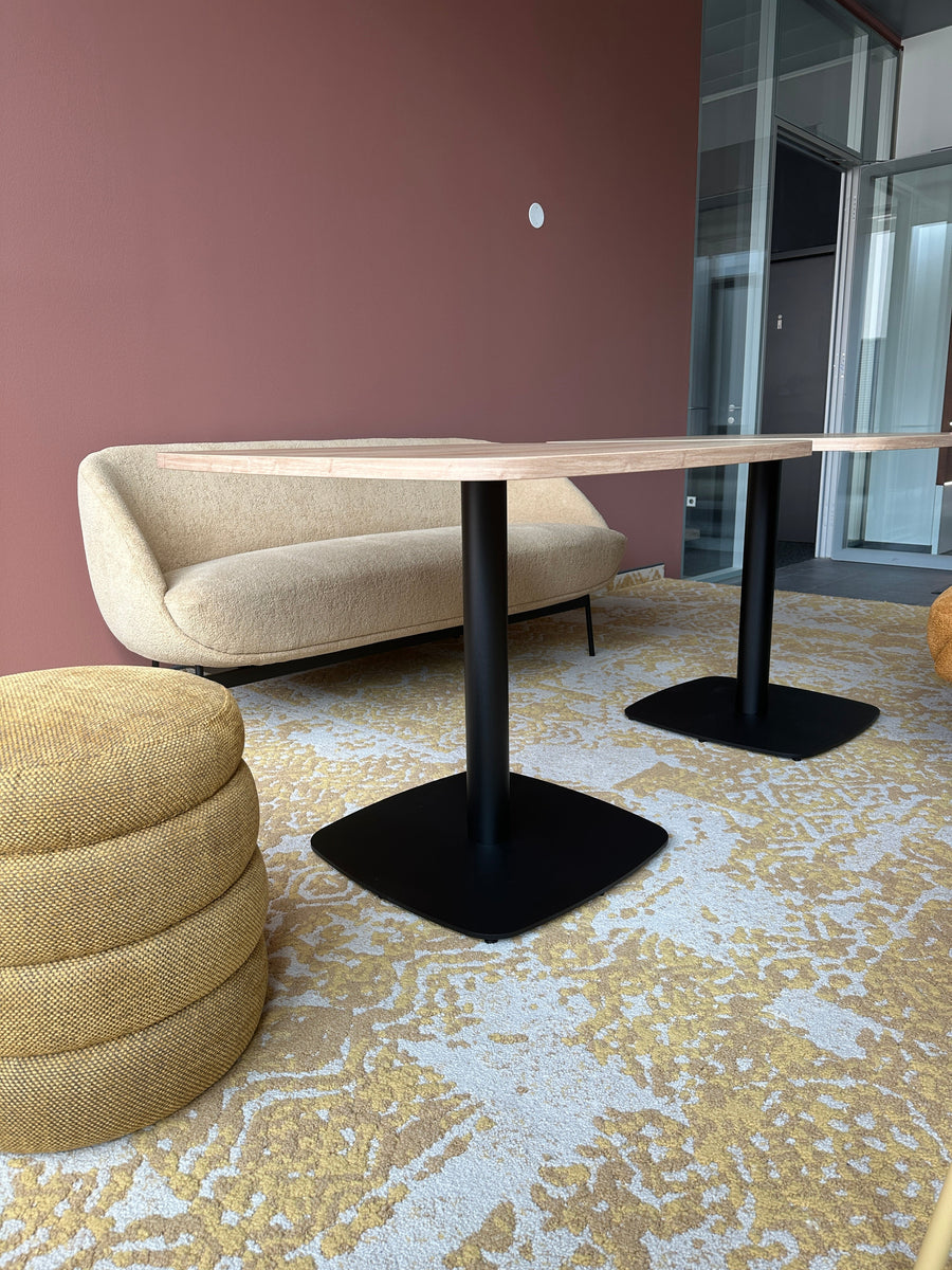 Loungebereich mit Sofa in Bouclé, Poufs und Beistelltischen auf gemustertem Teppich